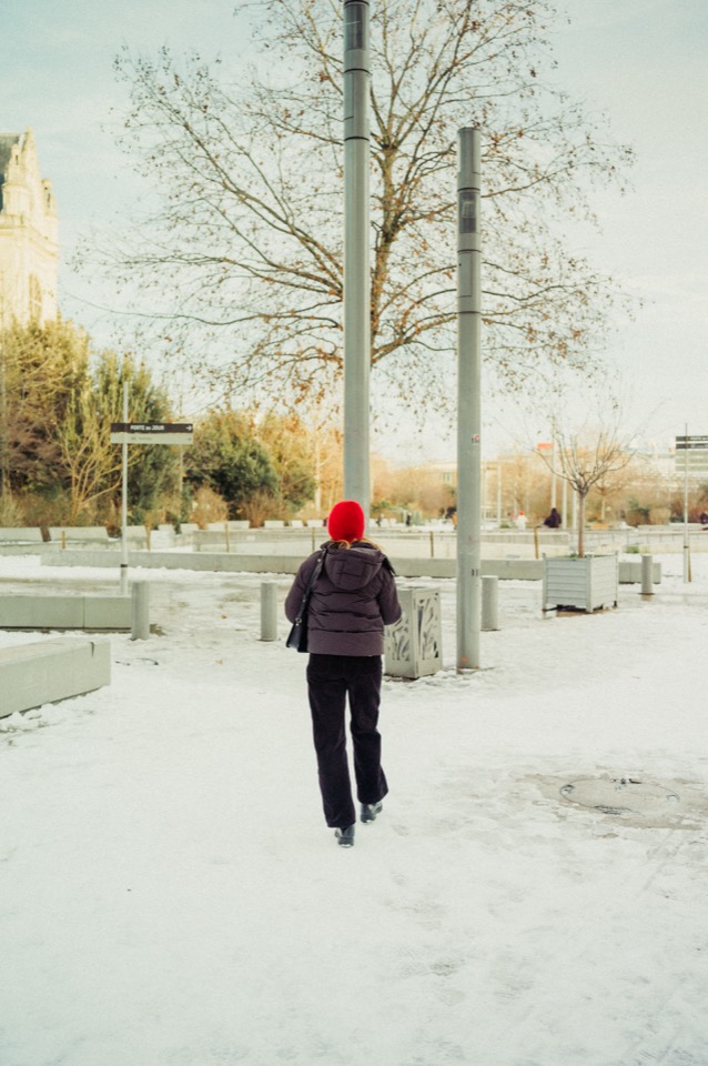 Person in red knit cap standing in a snowy plaza